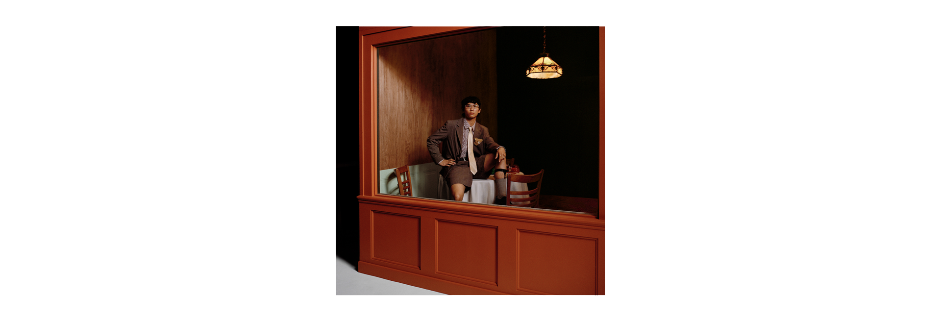 grentperez sitting at a desk in a dimly lit room with wooden paneling. 